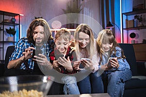 Two kids and their parents using smartphones at home