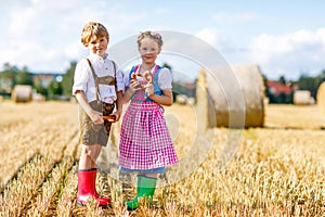 Two kids, boy and girl in traditional Bavarian costumes in wheat field