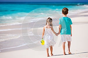 Two kids walking along a beach at Caribbean