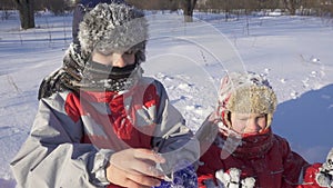 Two kids on winter park put on sticky snow glowes