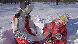 Two kids on winter park with sticky snow glowes