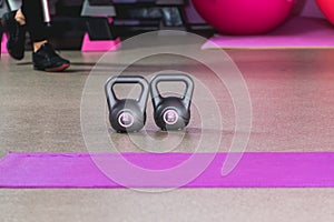 Two kilos in a grey colour weights in a sport studio with pink balls on the backround and sneakers