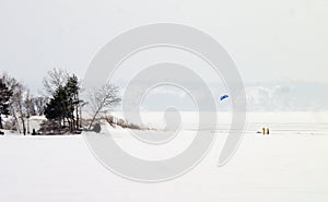 Two kiteboarders try to catching wind on the frozen lake.