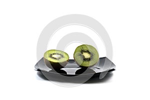 Two kiwis on a black plate, a side view