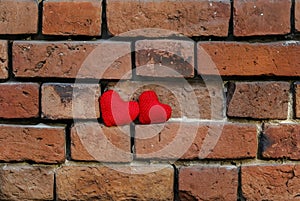 two knitted heart on a crumbling old red brick textured wall