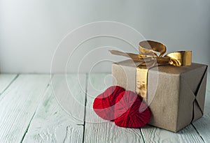 Two knitted hearts, gift box on rustic background