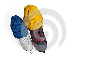 Two knitted winter hats of blue and yellow colors are put on men's and women's ice skates isolated on a white