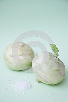 Two kohlrabies on a paper background. Light mint green background.