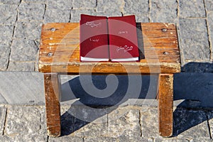 Two korans sitting on a grungy wooden table on cobblestone surface in sun with shadow