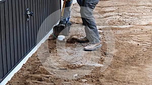 Two laborers move dirt at construction site after front loader backs away.