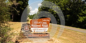 Two lane road passes exit sign to Kisatchie National Forest