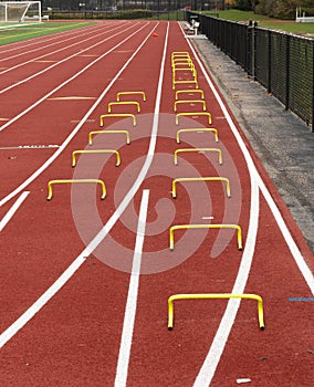 Two lanes on a track with yellow mini hurdles set up for the wicket drill