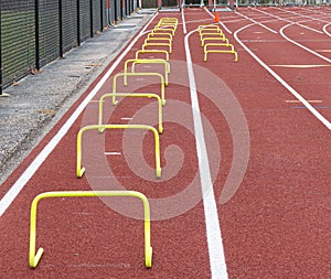 Two lanes on a track with yellow plastice hurldes of different sizes