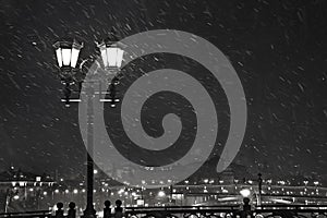 Two lanterns on the background of a night city and a snowstorm