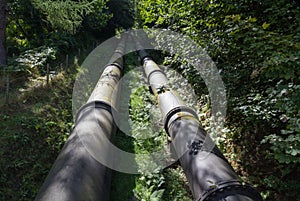 Two large black water pipes, converging in distance.