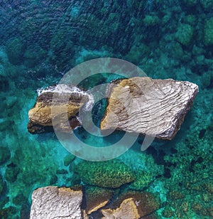 Two large boulders protrude from the water at the rocky shore. photo