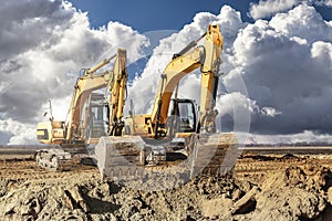 Two large excavator moving stone or soil in a quarry at a construction site. Heavy construction hydraulic equipment. Excavation