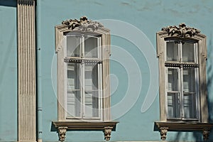 Two large gray old windows on the blue wall of a historic building