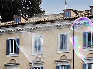 Two large iridescent soap bubbles against the facade of a building, Rome, Italy