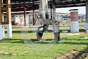 Two large pipes in insulation made of tin with red ventil, armature, valve, drainage at an oil refinery, petrochemical, chemical