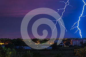 Two large and powerful lighting strikes crossing night blue sky