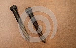 Two large vintage iron screws on a wood background
