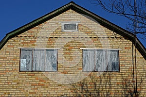 Two large windows on an old brown brick attic of a rural house