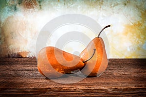 Two large yellow bosc pears on a barn wood table