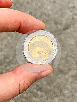 The two lari coin is held with two fingers