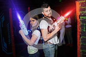 Two laser tag players standing back to back in bright beams