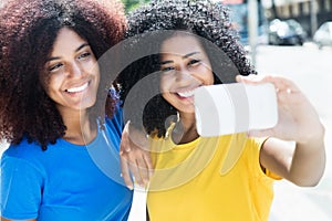 Two latin woman taking selfie with cellphone