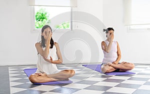 Two Latin yogi woman doing Nadi Shoddana Pranayama with Alternate Nostril breathing
