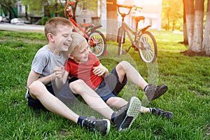 Two laughing boys having fun on the grass. Bicycles in the background