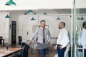 Two laughing businessmen talking together in an office