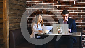 Two laughing coworkers discussing work project while on lunch break in cafeteria