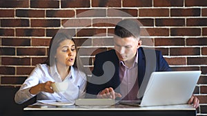 Two laughing coworkers discussing work project while on lunch break in cafeteria