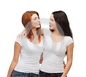 Two laughing girls in white t-shirts hugging