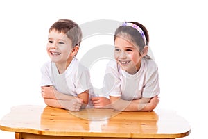 Two laughing kids at the desk looking aside