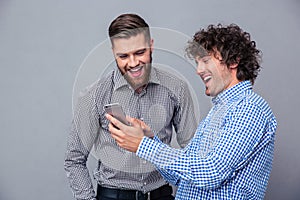 Two laughing men using smartphone