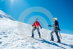 Two laughing to each other young women Rope team ascending Mont blanc du Tacul summit 4248m dressed mountaineering clothes with