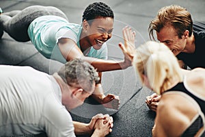 Two laughing women high fiving while planking at the gym