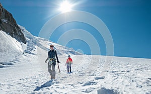 Two laughing young women Rope team descending Mont blanc du Tacul summit 4248m dressed mountaineering clothes with ice axes