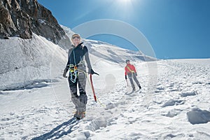 Two laughing young women Rope team descending Mont blanc du Tacul summit 4248m dressed mountaineering clothes with ice axes