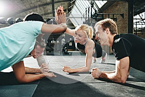 Laughing women high fiving together while planking at the gym photo