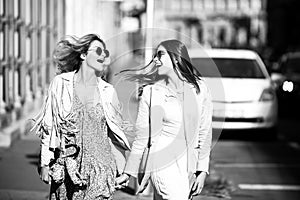 Two launching youngs women with sunglasses walking in the city. Funny vacation, romantic travel.