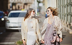 Two launching youngs women with sunglasses walking in the city. Funny vacation, romantic travel.