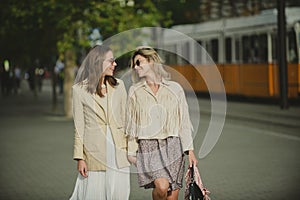 Two launching youngs women with sunglasses walking in the city. Funny vacation, romantic travel. Lifestyle urban mood.