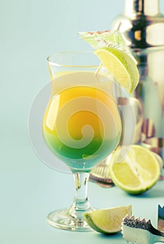 Two-layer alcoholic cocktail with mango juice, rum, liqueur, lime and ice, summer blue background, place for text