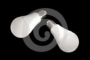 Two led bulb lights and energy-saving lamps on table on black background