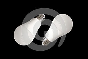 Two led bulb lights and energy-saving lamps on table on black background